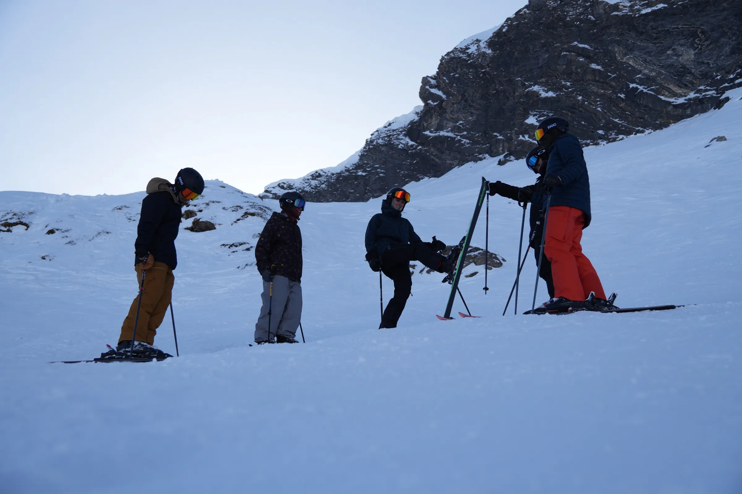 A GAP Course cohort regrouping below a rocky alpine face at dusk.