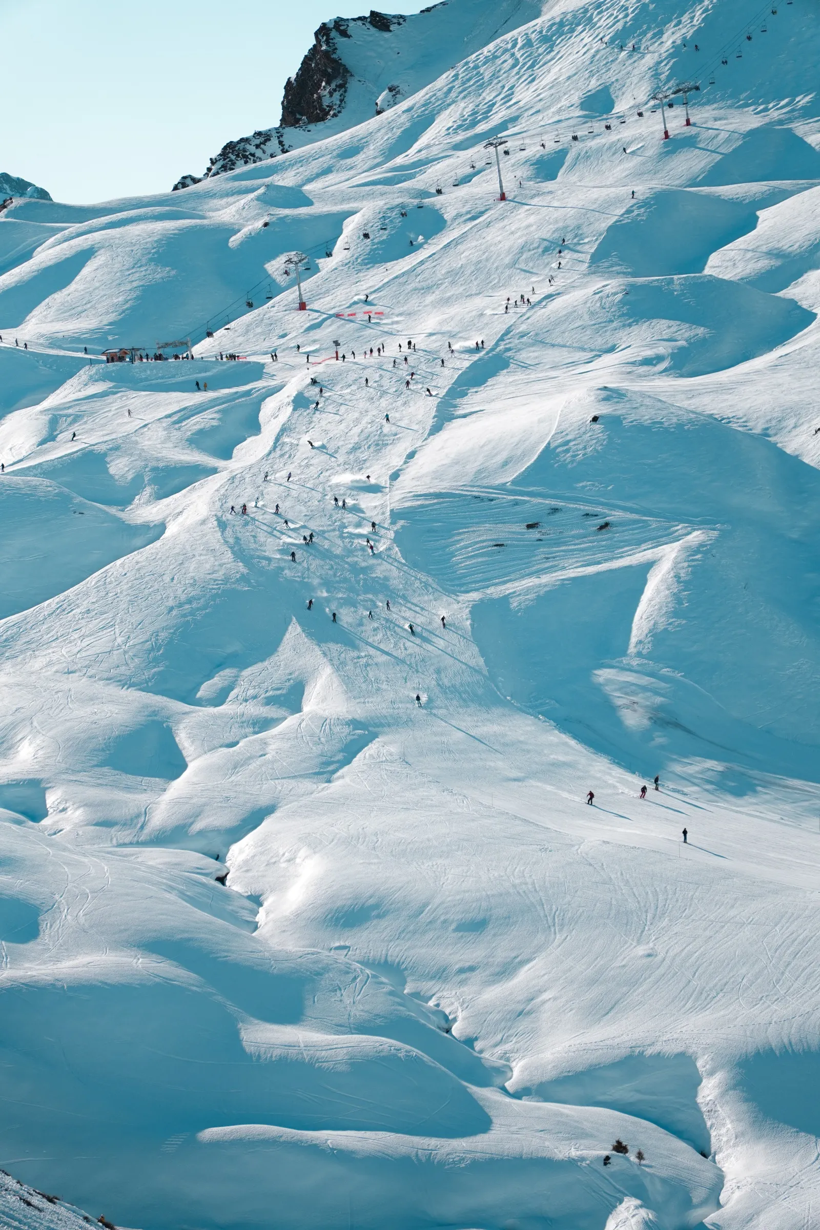 A Peak Snowsports coach with a small group of skiers on an alpine ridge.